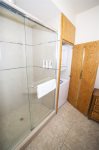 Master suite bathroom with glass encased shower, stackable washer dryer in cupboard